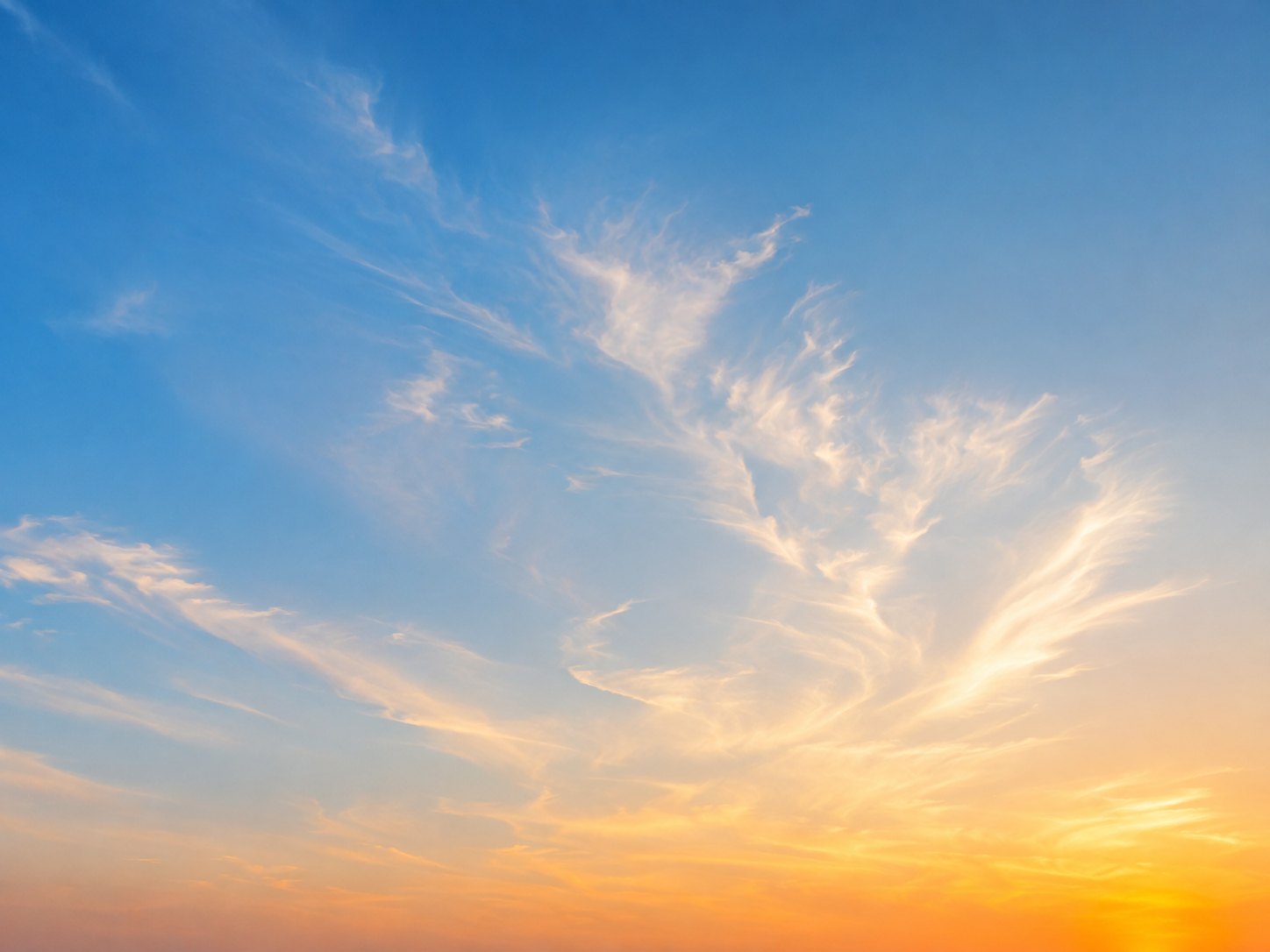 Fine white clouds in a blue and golden evening sky