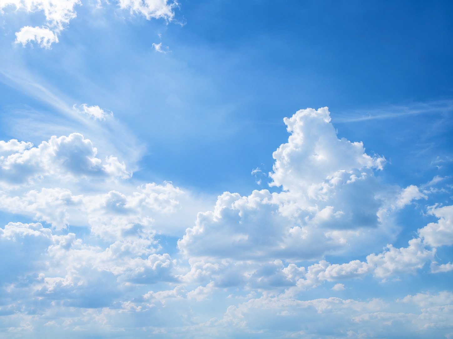 Bright white cumulus clouds in a clear blue summer sky
